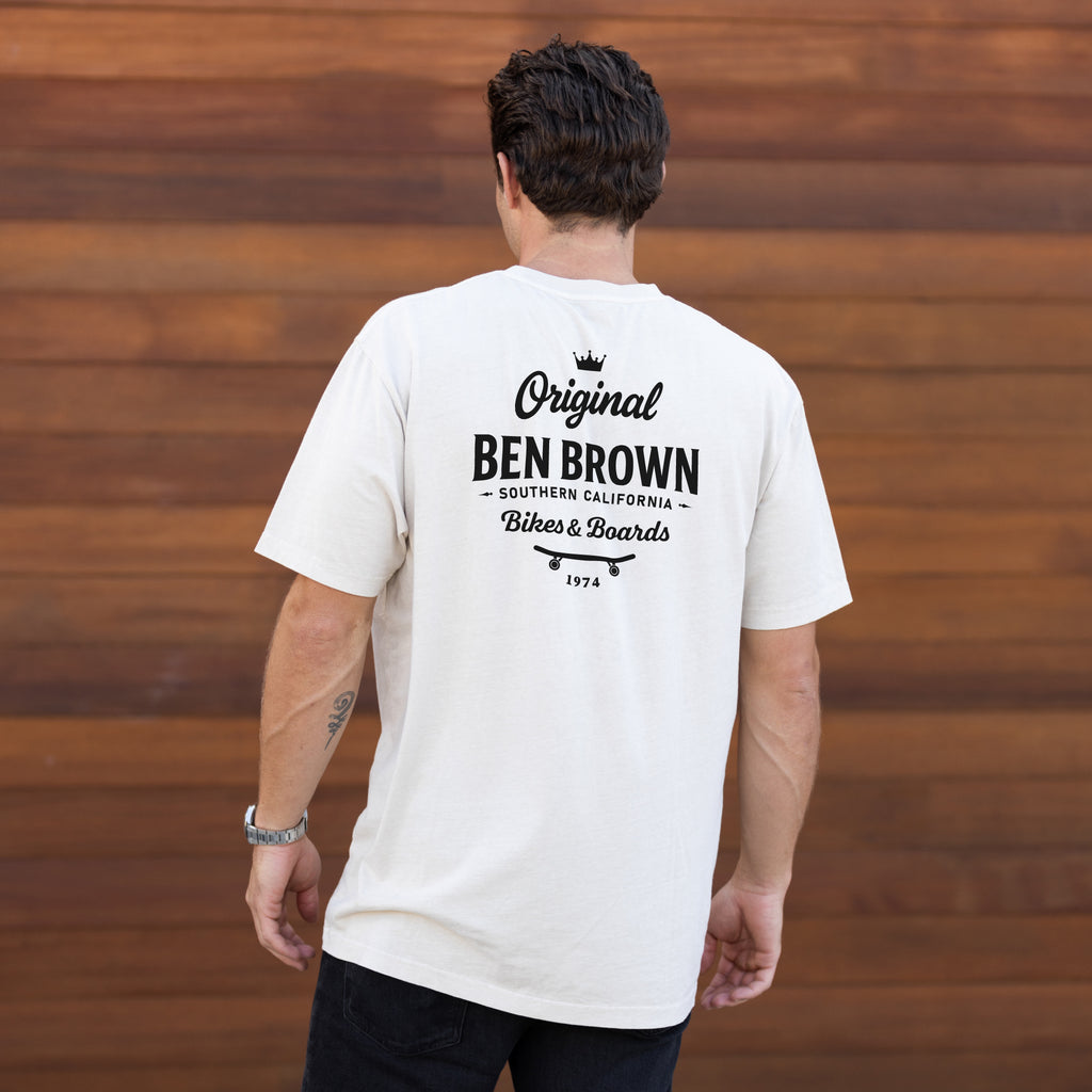 Man wearing a white t-shirt with 'Original Ben Brown' text on the back against a wooden wall.