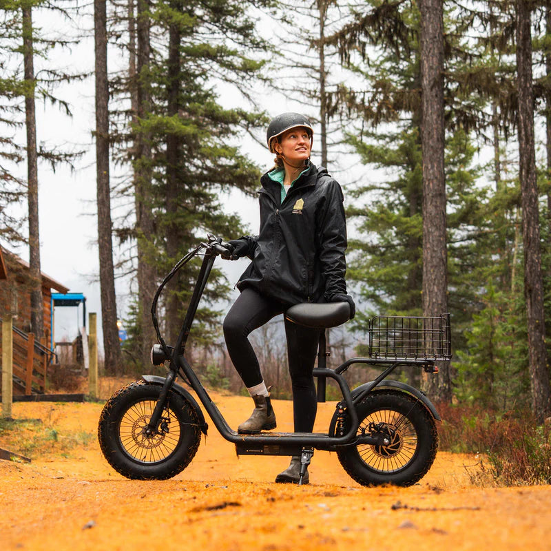 Rider standing with a Hiboy U2 Pro electric scooter on a forest trail
